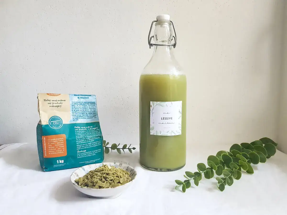 Ingrédients pour la meilleure recette lessive maison : percarbonate de soude, savon de Marseille râpé, dans une grande bouteille.