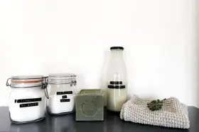 Ingrédients pour la meilleure recette lessive maison : bicarbonate de soude, cristaux de soude, savon de Marseille et une bouteille de lessive liquide.