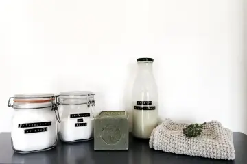 Ingrédients pour la meilleure recette lessive maison : bicarbonate de soude, cristaux de soude, savon de Marseille et une bouteille de lessive liquide.