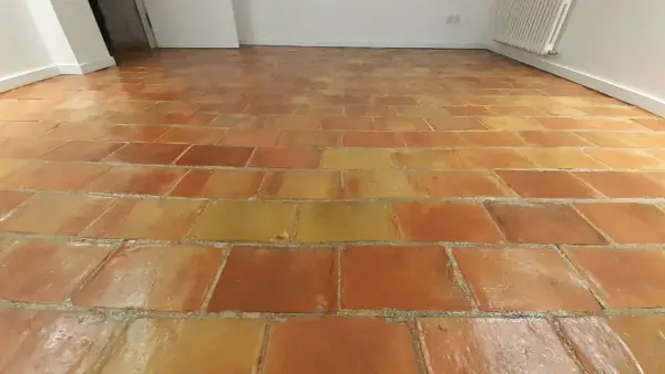 Sol en terre cuite aux tons chauds, avec un joint de barbotine visible entre les carreaux.