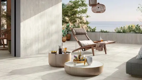 Terrasse avec pose travertin sur carrelage existant. Chaise longue, tables basses et vue mer. Ambiance détente.