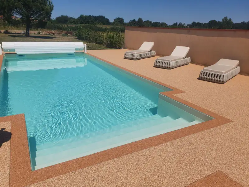 Piscine avec escalier, entourée de **pierre autour piscine** et de chaises longues.